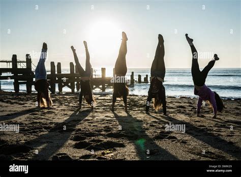 A Group Of 5 Five Teenage Girls Doing Handstands On Aberystwyth Beach