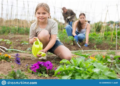 Daughter Helps Mother Clean Weeds In Farmer Garden Beds Royalty Free