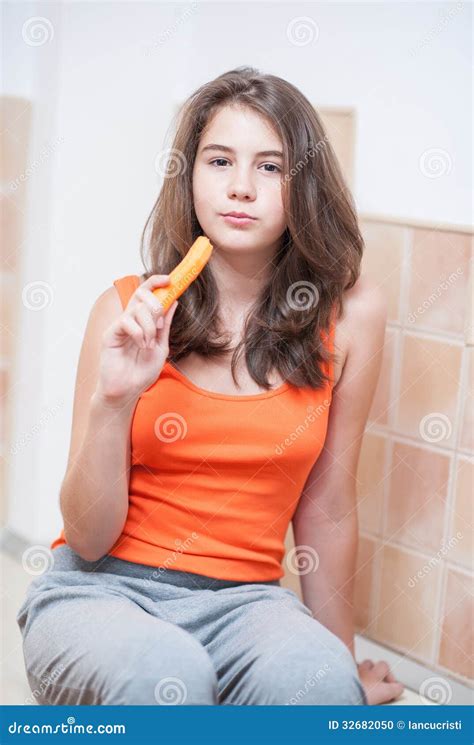 Девочка подросток в оранжевой футболке есть морковь Стоковое Фото изображение насчитывающей