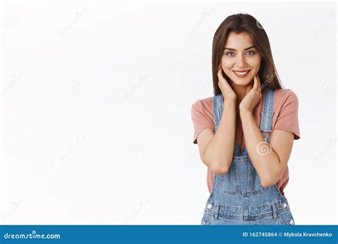 Attractive Alluring Brunette Woman In Dungarees T Shirt Touching Her Neck And Smiling With