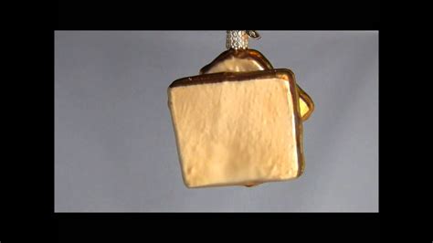 A glass ornament featuring a mouse and block of cheese shape with glitter details and a string loop for easy hanging. 32187 Old World Christmas Grilled Cheese Sandwich Glass ...