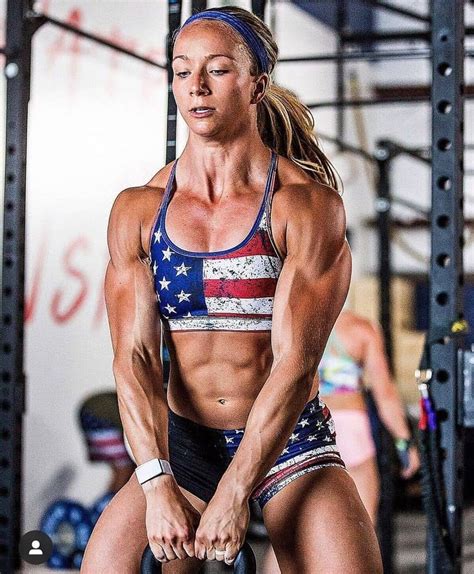A Female Bodybuilt Competitor Posing For The Camera With Her Barbells