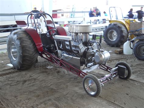 two large tractors are parked in the sand near some people and other