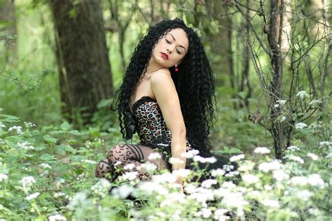 Фото Девушка с кудрявыми длинными волосами сидит в лесу на поляне By Adinavoicu