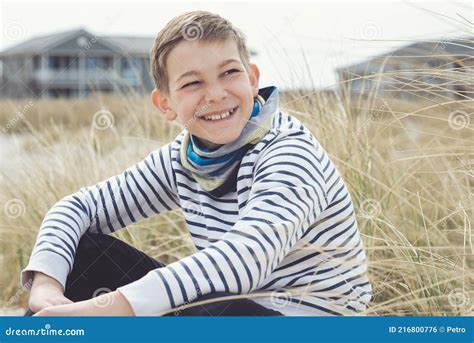 Portrait Of Handsome Teenage Boy Sitting And Smiling On White Sand On
