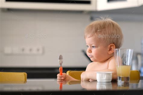 Adorable One Year Old Baby Boy Eating Yoghurt With Spoon Stock Photo By