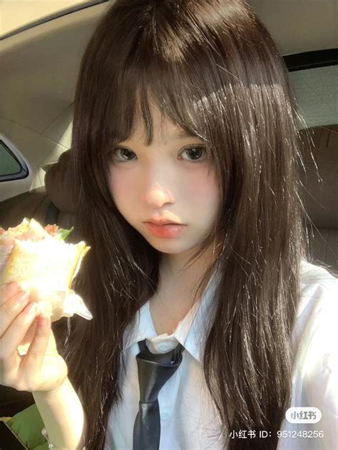 A Girl In A Tie Is Holding A Sandwich And Looking At The Camera While Sitting In A Car