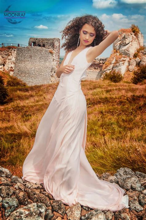 A Woman In A White Dress Standing On Rocks