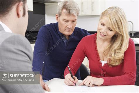 mature couple with financial advisor signing document at home superstock