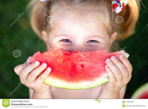 Closeup Portrait Of Cute Little Girl Eating Watermelon On The Grass In