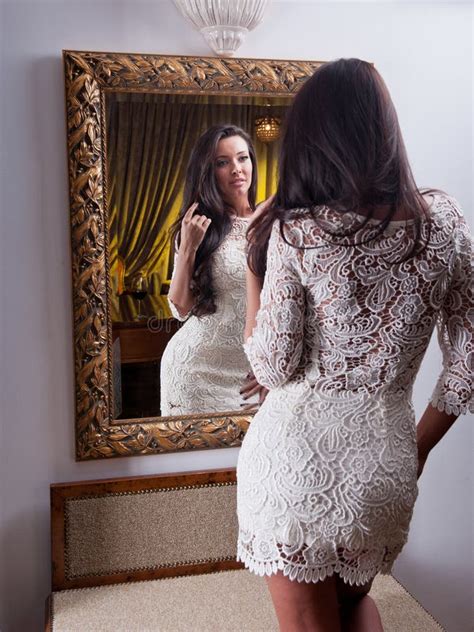 The Beautiful Girl In A Short White Dress Looking Into Mirror Stock