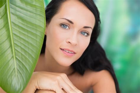premium photo beautiful nude brunette smiling at camera with green leaf
