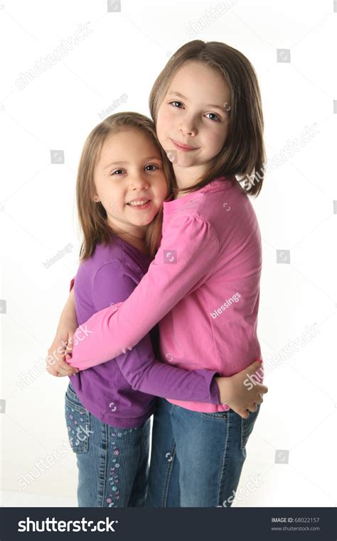 Two Cute Young Sisters Standing Up Hugging Each Other Isolated On