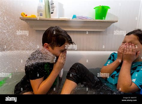 Twin Caucasian Brothers Play In Their Water Filled Bathtub Together With Their Clothes On Stock
