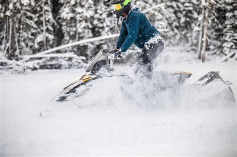 Side View Of Man Snowmobiling Through Deep Snow Stock Photo