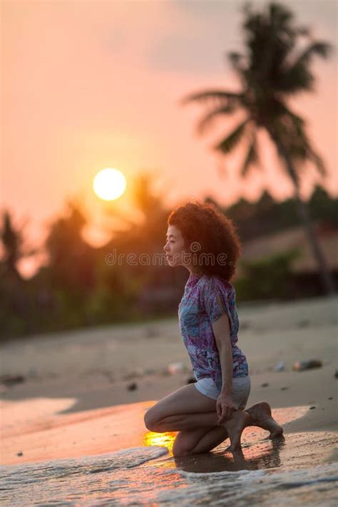 Young Woman Kneeling On A Tropical Beach During An Amazing Sunset
