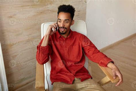 Indoor Photo Of Young Pretty Dark Haired Bearded Guy Making Phone Call