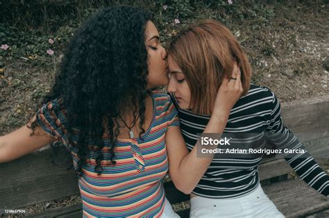 Two Lesbian Couple Of Different Racial Ethnic Kissing On A Bench Stock