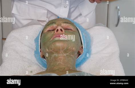 Cosmetician Hands Applying Cleansing Foam On Womans Face With Green Mask Stock Video Footage