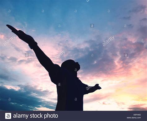Low Angle View Of Silhouette Man With Arms Outstretched Against Sky