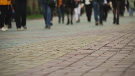 Timelapse crowds of people walking on city pavement tiles. The footsteps of a crowd of people go ...
