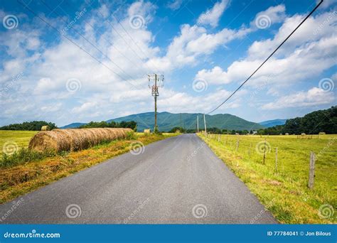 Country Road With Distant Mountains And Farm Fields In The Rural Stock