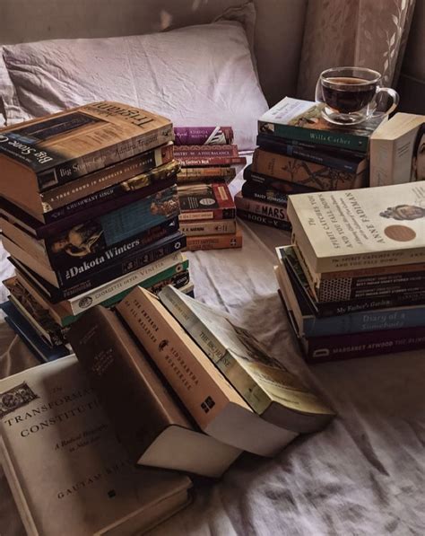 A Pile Of Books Sitting On Top Of A Bed Next To A Glass Of Wine
