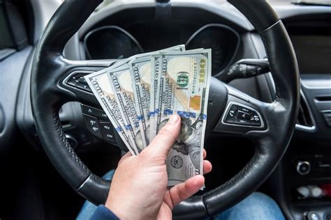 Premium Photo Man Gives Dollars While Sitting In The Car Concept Of