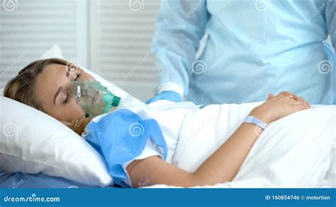 Female Patient In Oxygen Mask Sleeping Nurse Standing By Surgery