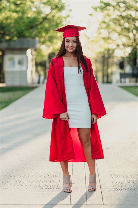 A Woman In A Graduation Gown And Cap Is Standing On The Sidewalk With