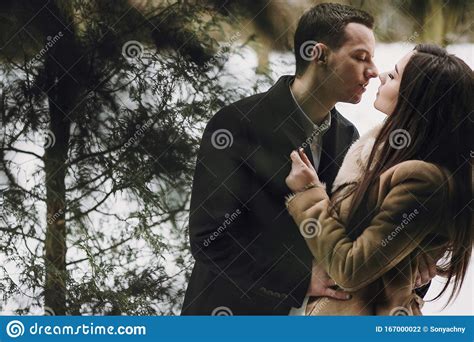 Gorgeous Wedding Couple Kissing In Winter Snowy Park Stylish Bride In Coat And Groom Embracing