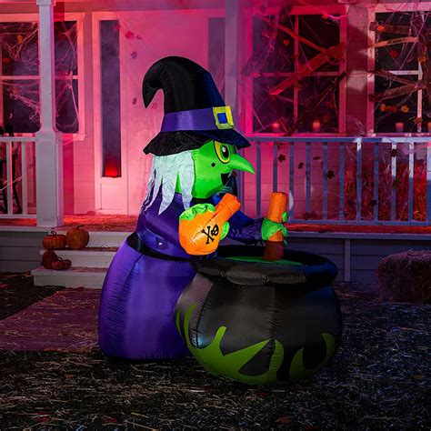 A Large Inflatable Witch Sitting On Top Of A Potted Plant Next To A House