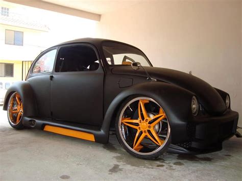 An Orange And Black Vw Bug Is Parked In A Garage Next To A Building