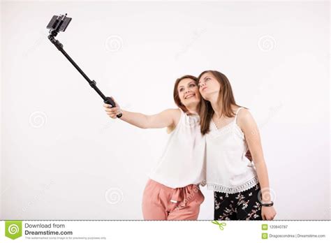 Two Beautiful Young Woman Taking A Selfie With A Selfie Stick Stock