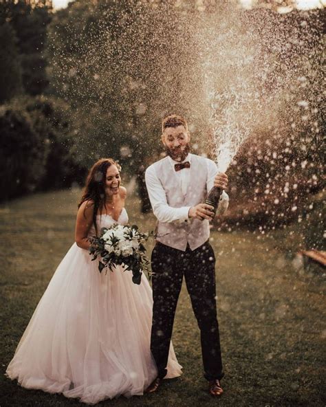 A Bride And Groom Are Standing In The Rain With Confetti Falling From