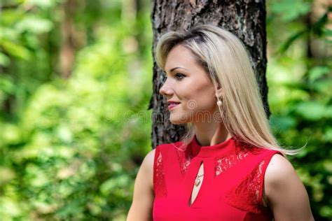 Beautiful Blonde Woman In Red Dress Walking Through The Forest Stock