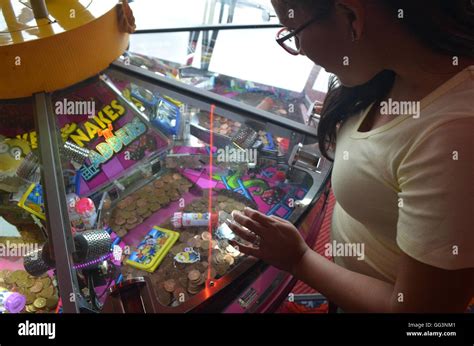 A Girl Playing On The Coin Slot Machines In A Seaside Funfair In Whitby