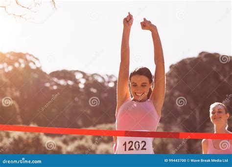 Happy Female Athlete With Arms Raised Crossing Finish Line Stock Photo