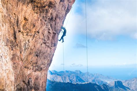 Premium Photo Rock Climber Climbing Up Overhanging Cliff With Canary