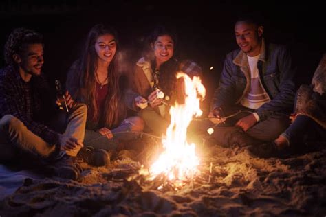 Friends Laughing Around A Campfire At Night Stock Photos Pictures