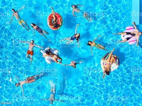 Aerial Of Friends Having Party In Swimming Pool With Inflatable