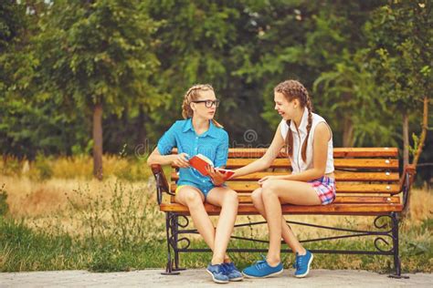 Best Friends Are Discussing Book Sitting On Bench Stock Image Image
