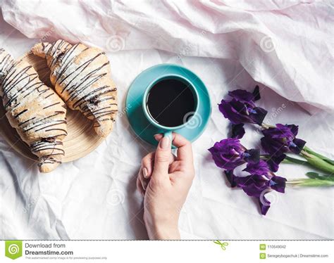 Woman Hands Holding Cup of Coffee in Bed. Beautiful Flowers and a Watch ...