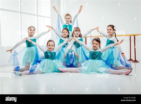 Smiling Little Girls In Dresses Practicing Postures During Ballet Class