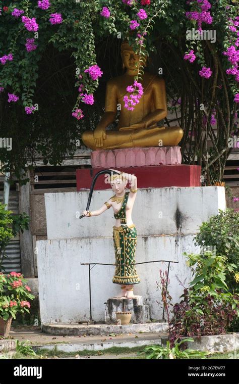 Une Statue De Phra Mae Thorani Lavant Ses Cheveux Devant Une Statue De Bouddha Assise Luang