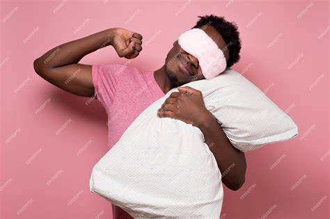 Афро американский темнокожий мужчина спит обнимая подушку в маске для