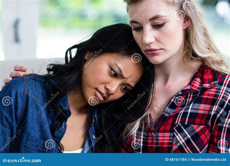 Young Woman Consoling Depressed Female Friend At Home Stock Photo