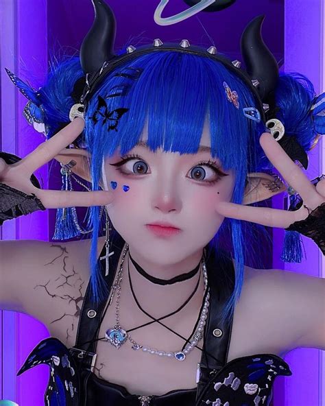 A Woman With Blue Hair And Horns On Her Head Wearing Black Leather