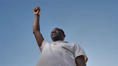 Low Angle View Of Confident Dark Skinned Man Standing With Raised Hand