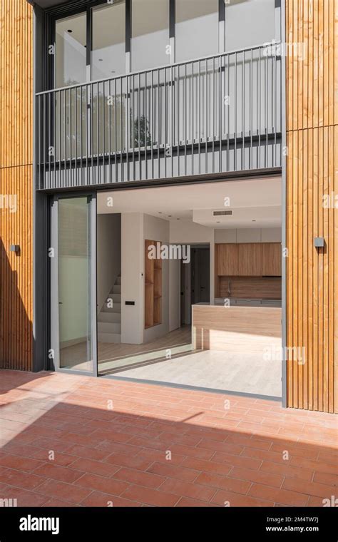 Glass Doors In Black Metal Frame Open Onto House With Spacious Kitchen